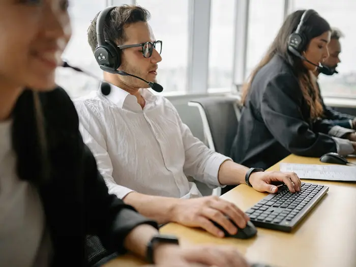 4 personnes portant des casques micro et travaillant sur leurs ordinateurs