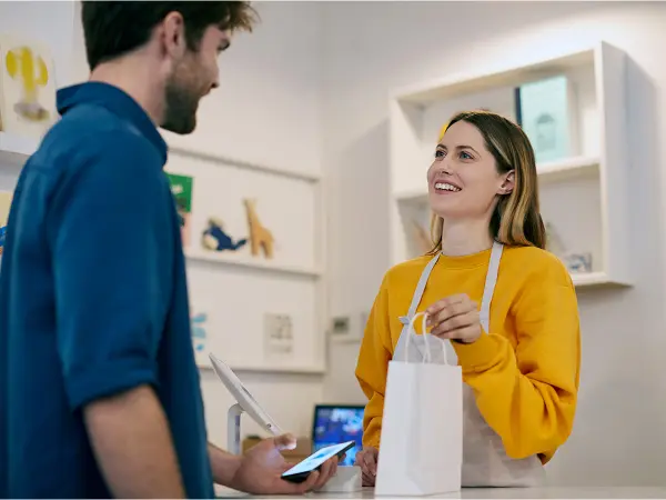 Une vendeuse remettant un sac à un client