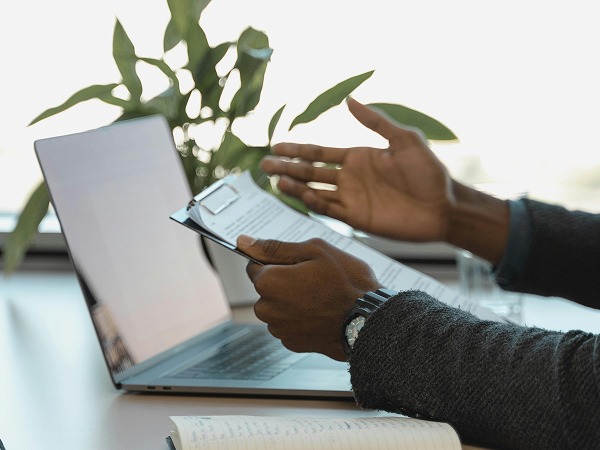 Une personne tenant des documents devant un ordinateur