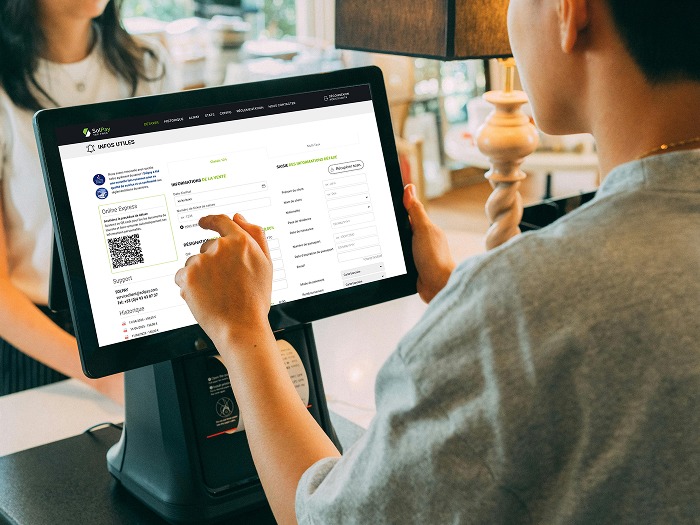 Un vendeur en caisse utilisant le logiciel Solpay sur son écran de caisse face à un client