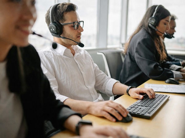 4 personnes portant des casques micro et travaillant sur leurs ordinateurs