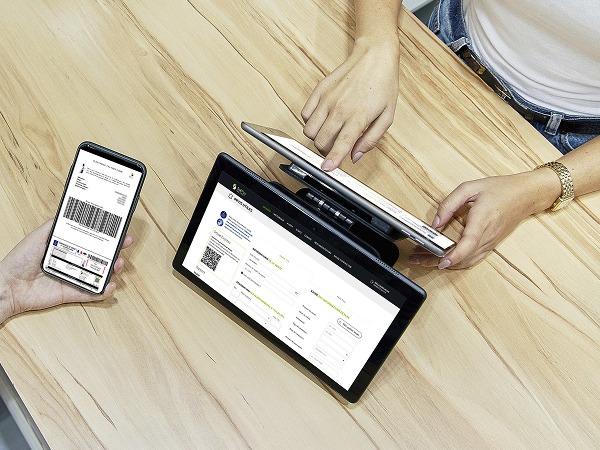 Une personne utilisant une tablette face à une personne présentant une facture sur son téléphone