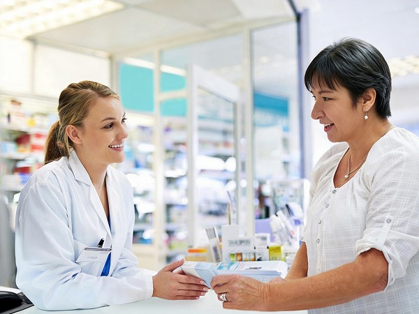 Une pharmacienne en train de discuter avec une femme au comptoir de la pharmacie